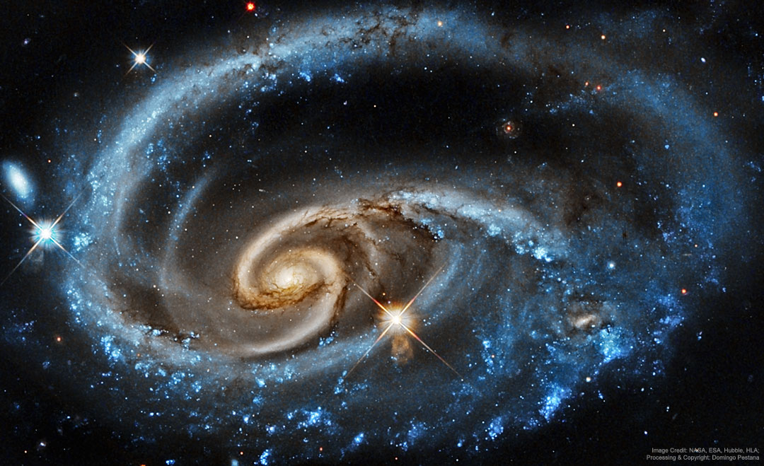 A bright galaxy with unusual blue spiral arms is shown against a dark starfield. The outer part of the spiral appears as a blue ring, while the inner part appears to have separate -- and more tan -- spiral structure. Please see the explanation for more detailed information.