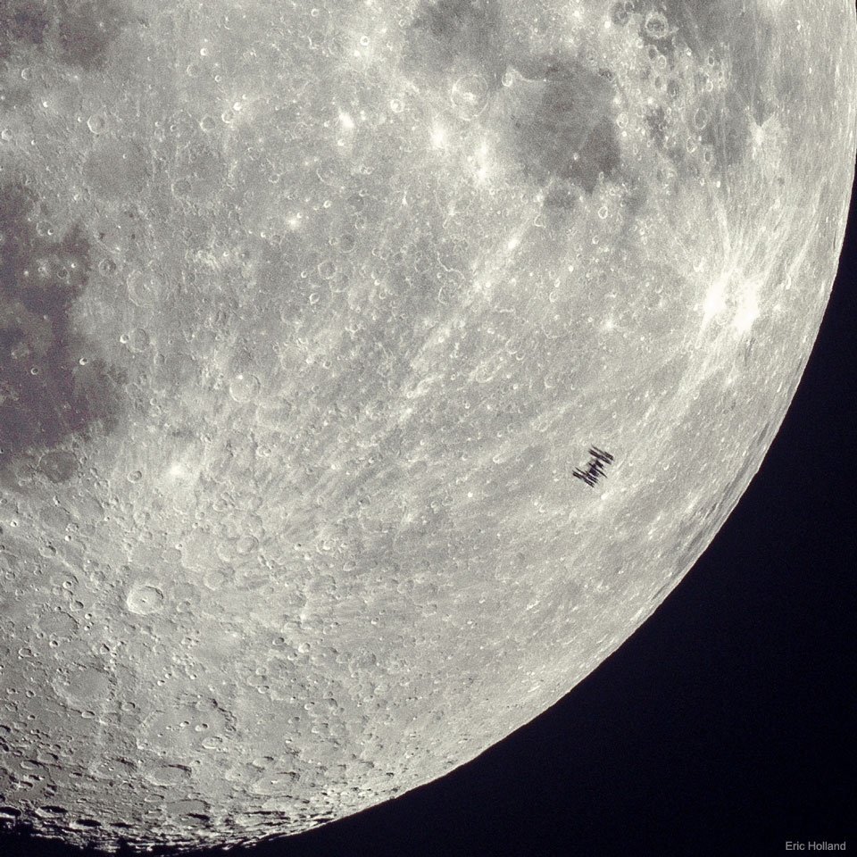 A detailed view of part of Earth's Moon is shown with many craters visible. On the lower right, silhouetted against the comparatively bright Moon, is a small dark silhouette of the International Space Station. Many of the solar panels on the station are discernable. Please see the explanation for more detailed information.