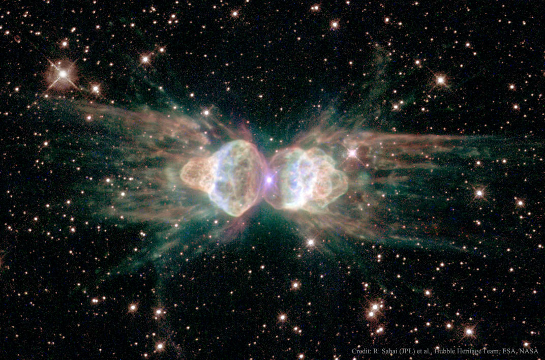 A dark starfield appears around an unusually shaped nebula. The nebula has two main lobes on the left and the right and may seem to resemble an ant. Please see the explanation for more detailed information.
